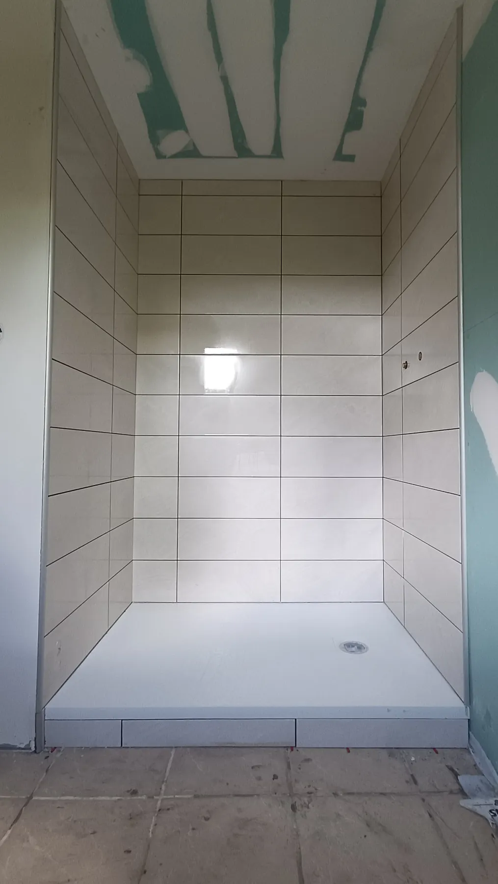 Douche en grands carreaux blancs au-dessus d’un receveur extra-plat