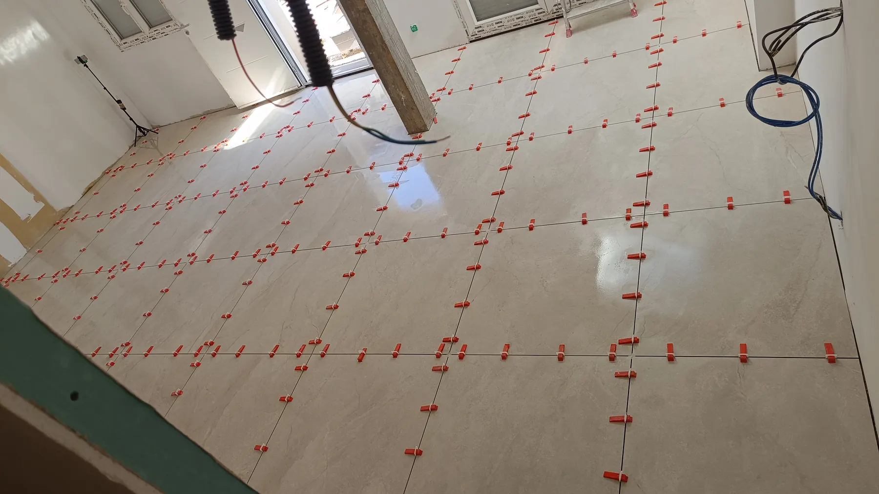 Large marble-effect tiles being laid and set with a levelling system