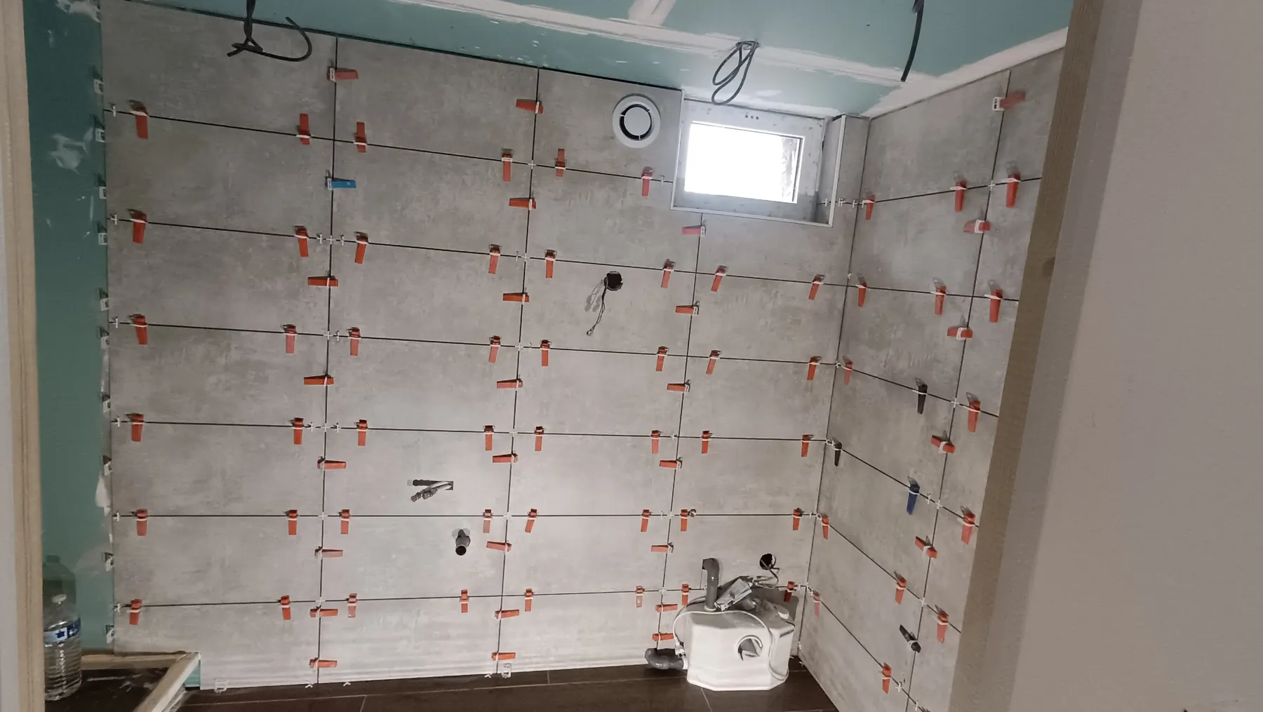Large white wall tiles being laid with a levelling system