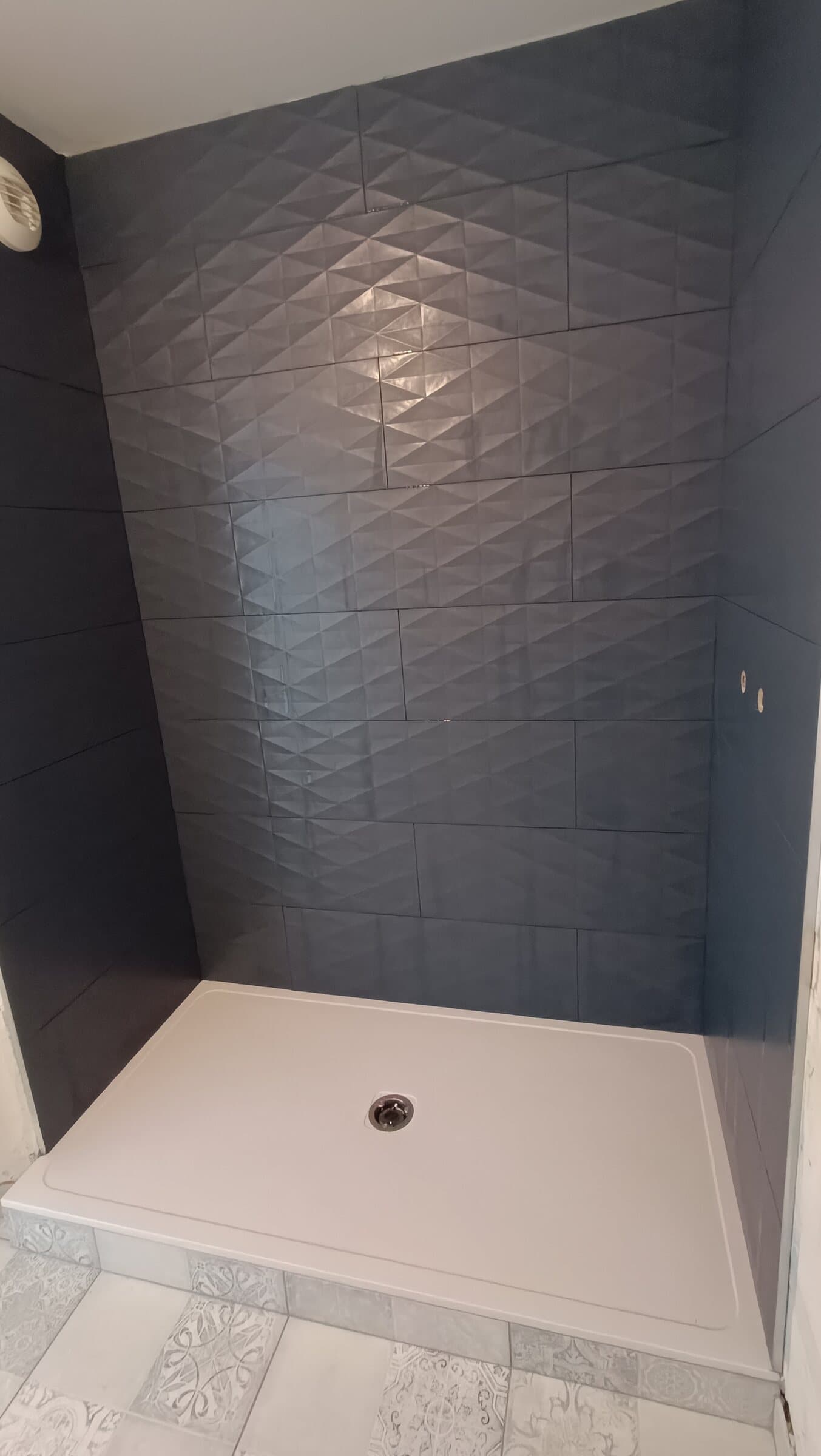Douche habillée de faïence anthracite à relief géométrique, avec un receveur blanc