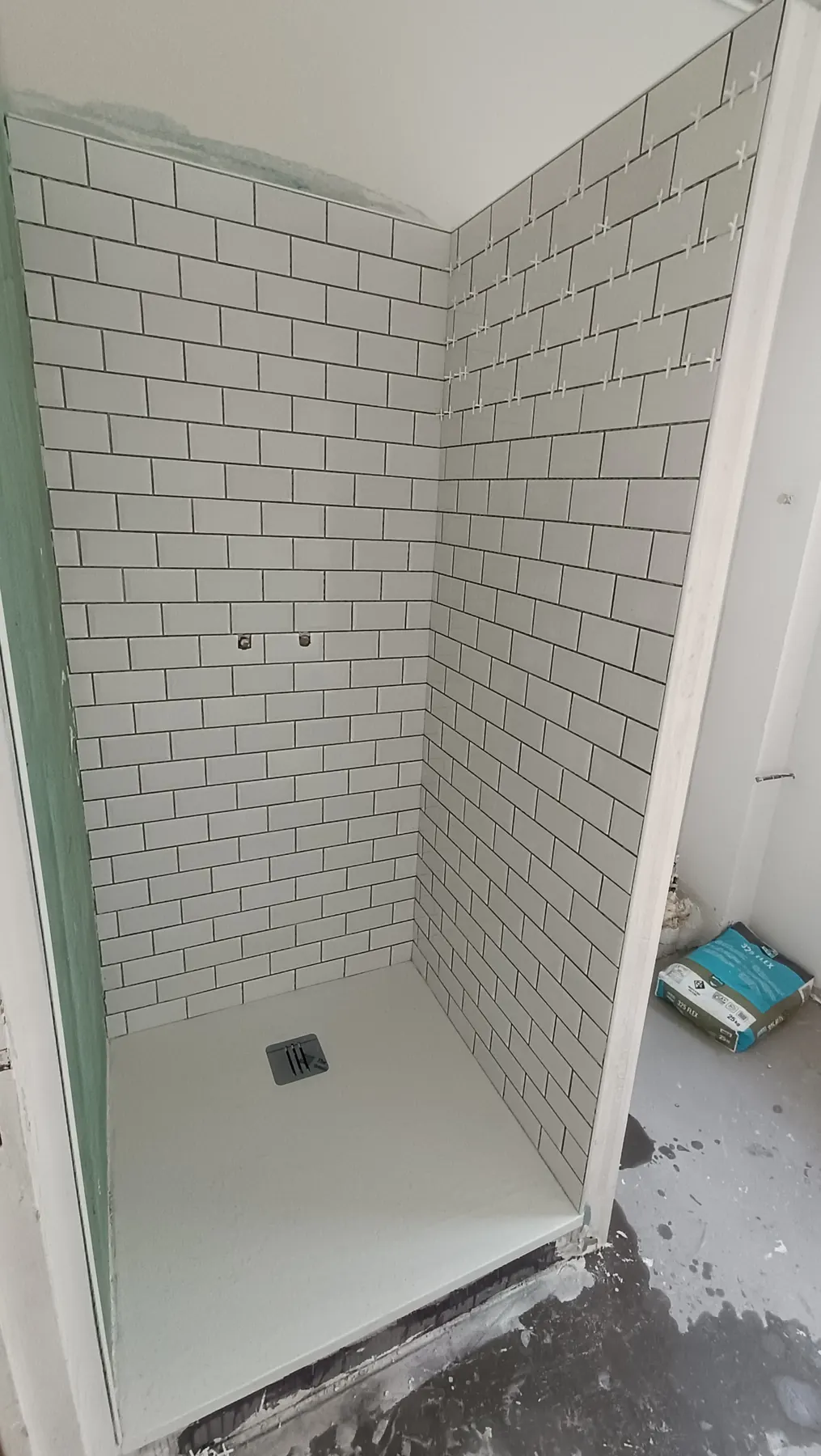 Shower in white metro tiles with dark grey grout
