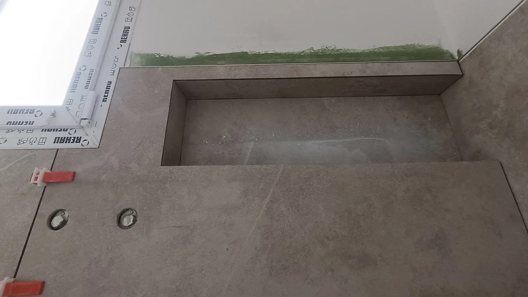 Wall niche tiled in stone-effect tiles above a bath