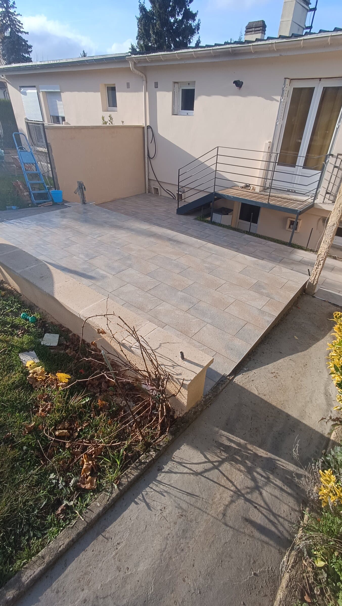 Terrasse extérieure en carrelage effet pierre dans le prolongement de la maison